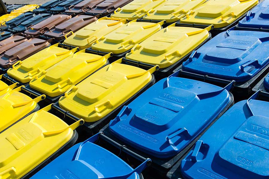 Blick von oben auf Abfalltonnen mit blauem, gelben und braunem Deckel.