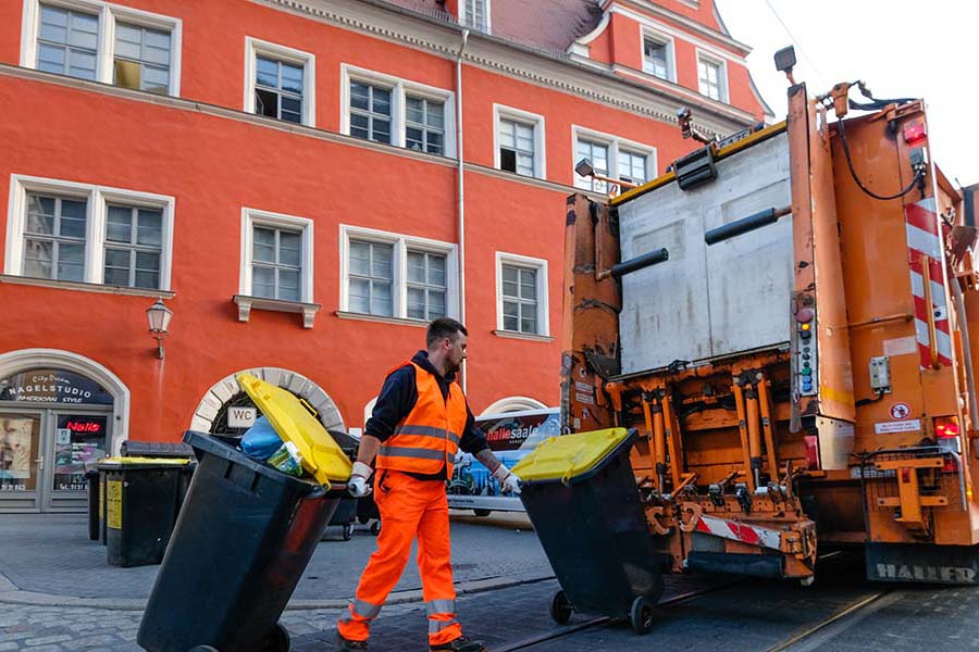 Mitarbeiter leert Mülltonnen am Müllwagen.