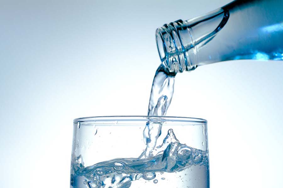 Wasser wird in Trinkglas eingeschenkt.