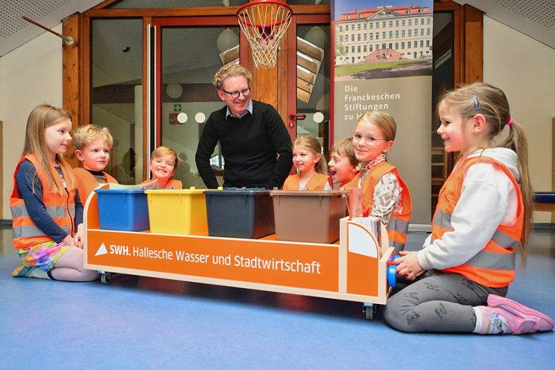 Peter Günther, Geschäftsführer der HWS und Kinder einer Kita spielen das neue Mülltrennspiel