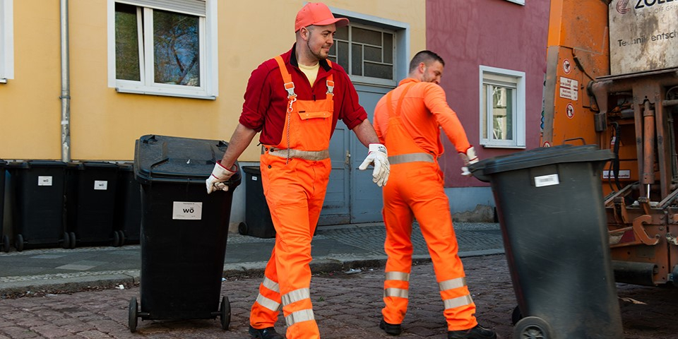 Zwei Mitarbeiter mit Mülltonnen.