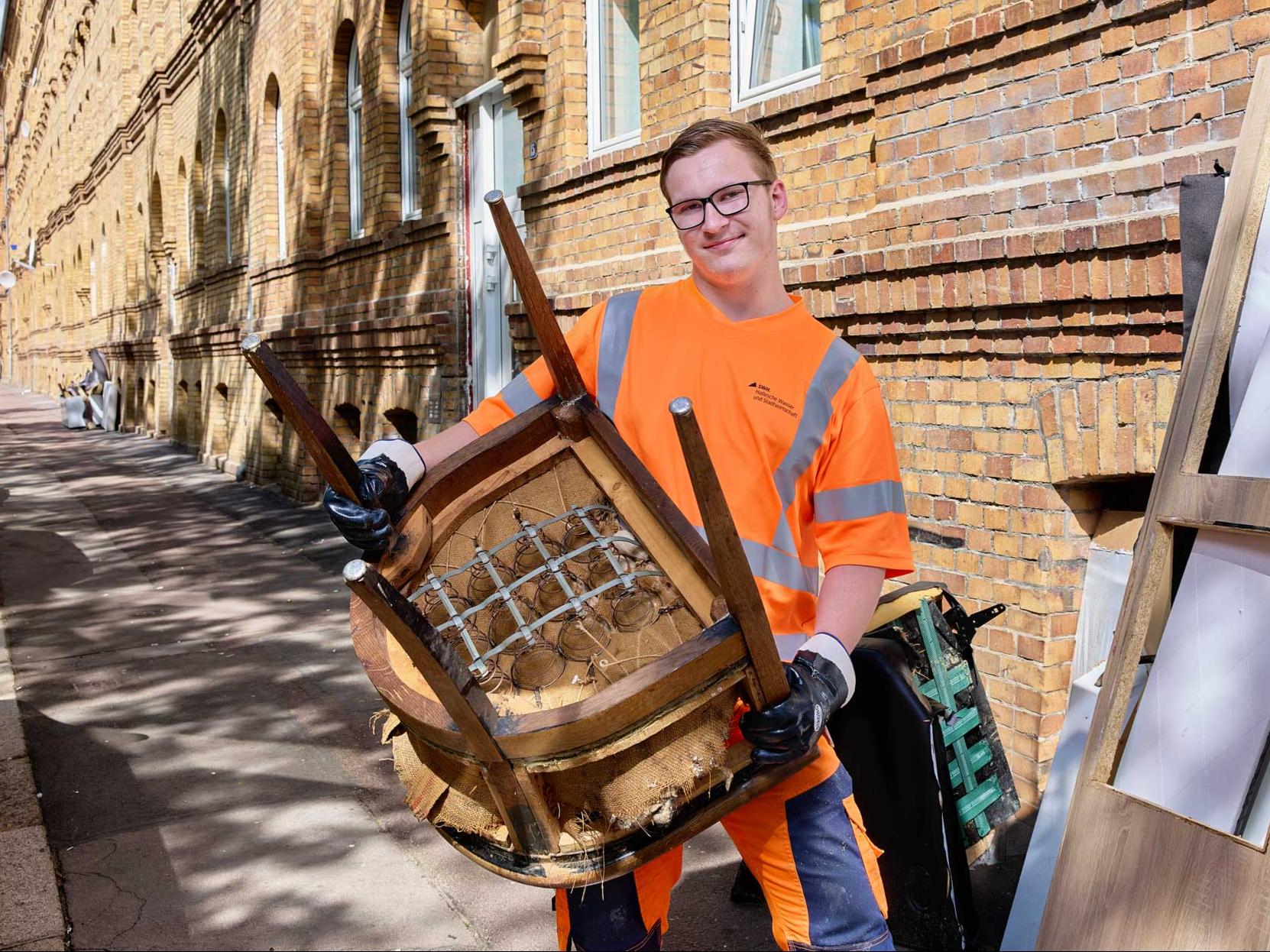 Mitarbeiter mit Stuhl neben weiterem Sperrmüll.