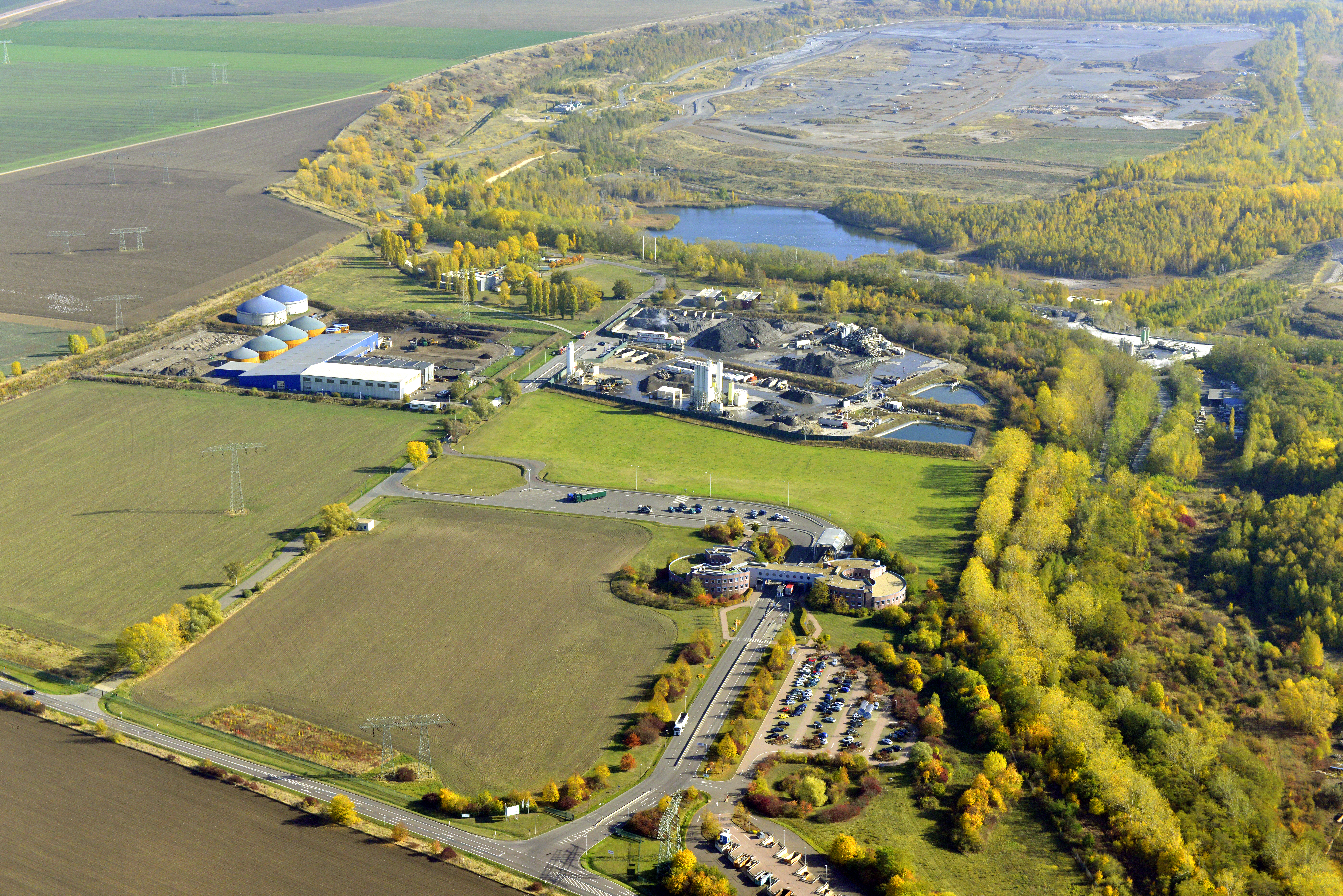 Das Bild zeigt eine Luftaufnahme vom Areal der Abfallwirtschaft GmbH Halle-Lochau. Etwa 2/3 des Bildes sind Wald, Rasen oder Seen. 