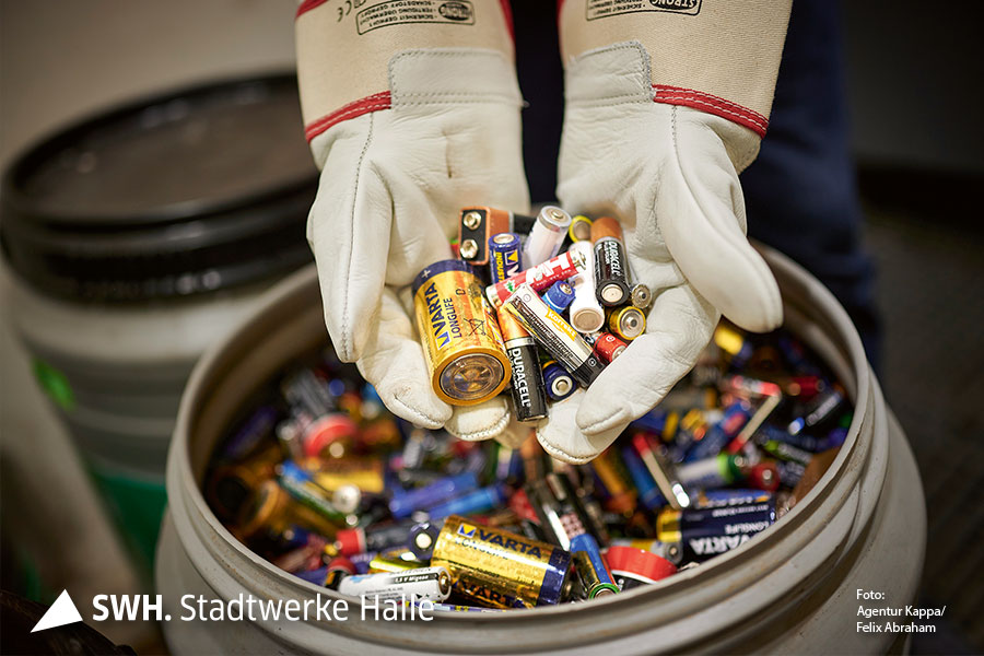 Zahleiche Batterien liegen in den Händen und darunter befindet sich ein Sammelbecken voller Batterien.
