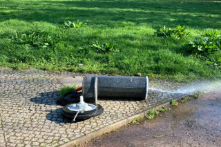 Beschädigter Trinkbrunnen liegt umgekippt auf der Wiese der Peißnitz.